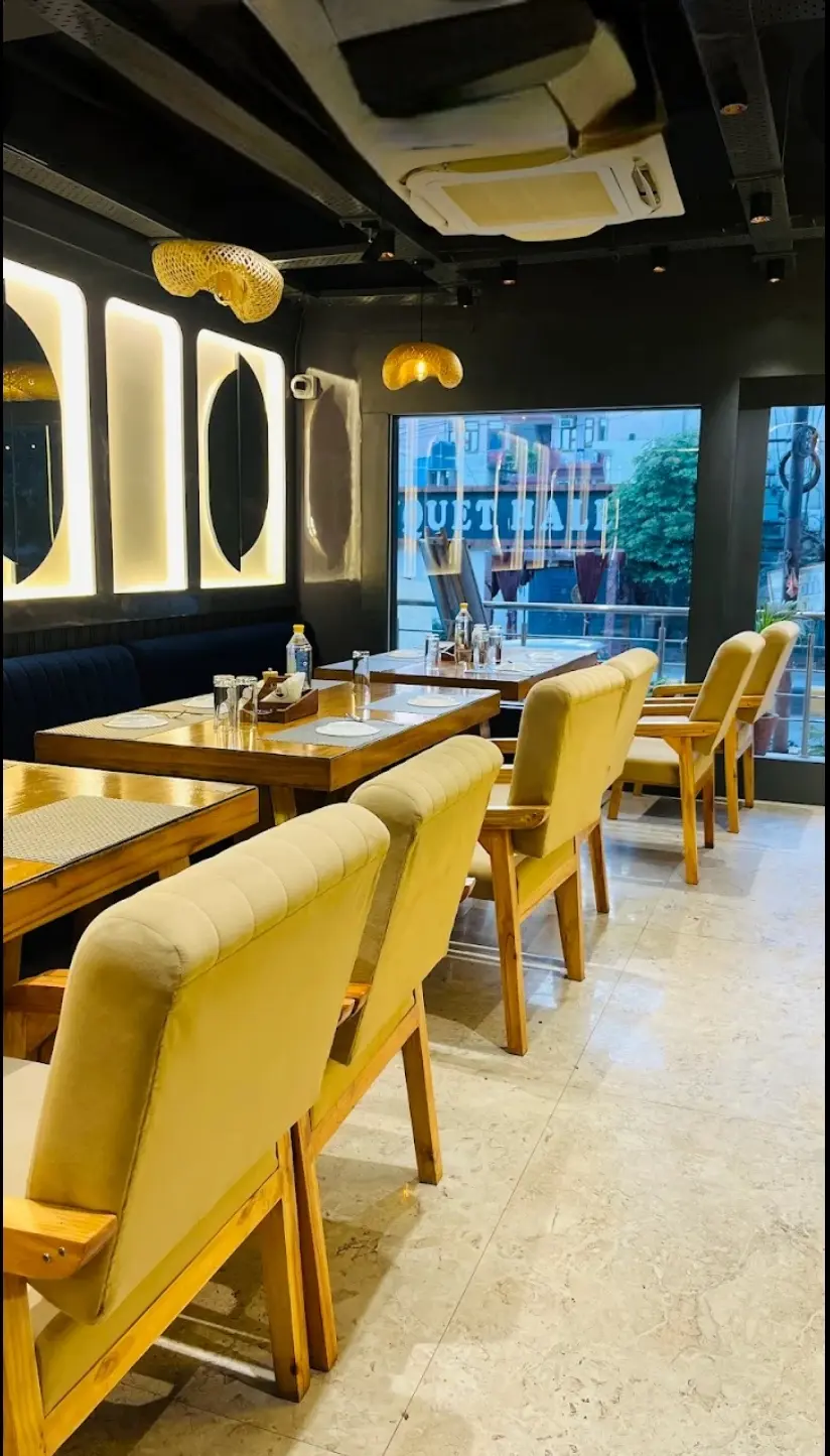 Warm dining room at The Dough Knot with velvet chairs, wooden tables and lit arches