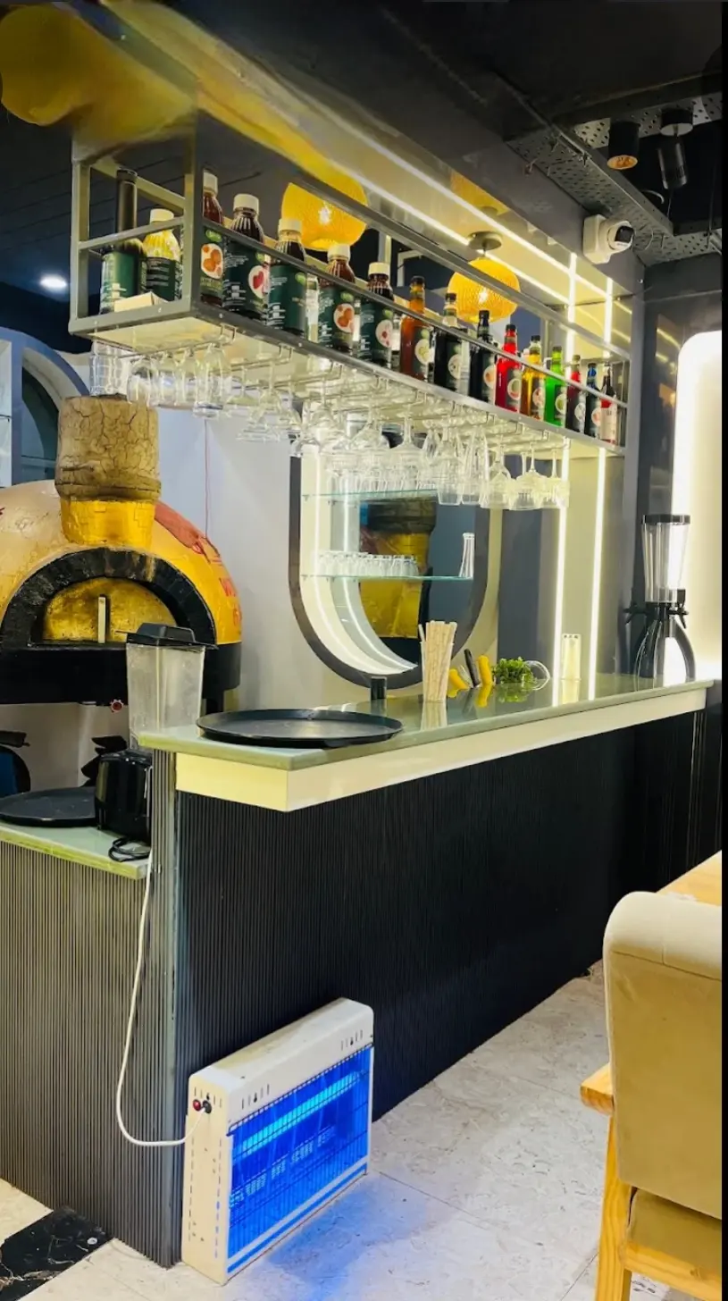 The wood-fire oven beside the bar with hanging glasses